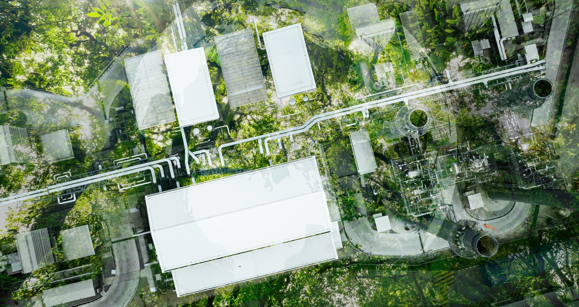 Luftaufnahme einer modernen, nachhaltigen Fabrikanlage mit grünen Dachflächen und umweltfreundlicher Infrastruktur, eingebettet in eine natürliche Umgebung.