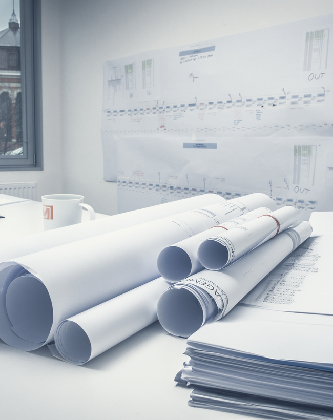 Architektenpläne und Bauzeichnungen auf einem Schreibtisch als Teil der detaillierten Entwurfsplanung für ein Bauprojekt.