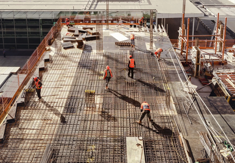 Bauarbeiter arbeiten auf einer Baustelle an einer Stahlkonstruktion und betreiben Fortschrittskontrolle und Bauüberwachung.