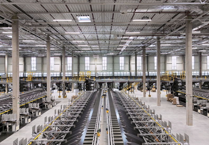 Modernes Logistikzentrum mit automatisierter Fördertechnik zur Optimierung von Materialfluss und Lagerverwaltung.